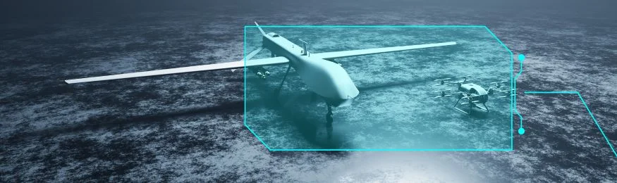 A fixed-wing military drone on a dark surface inside a highlighted bounding box