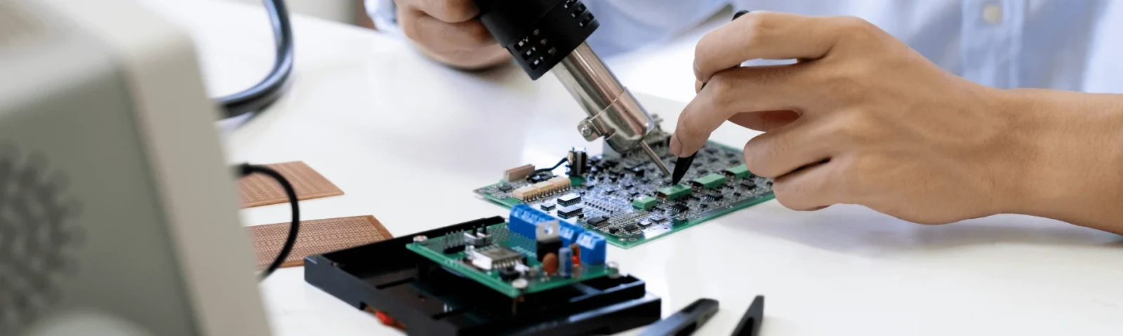 An engineer soldering components on a green circuit board