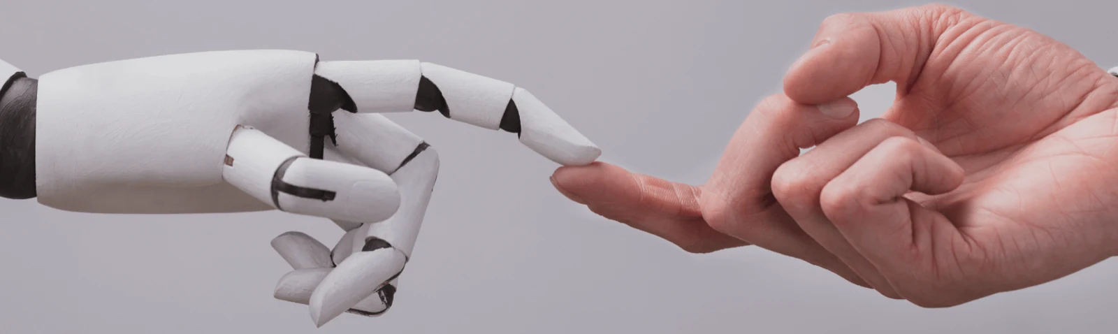 A robotic hand and a human hand reaching towards each other, fingertips almost touching