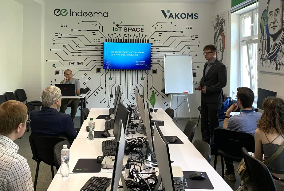 Speaker presenting a Horizon Tracer IoT GPS-tracking slide to an audience in the Indeema and Vakoms IoT Space lab