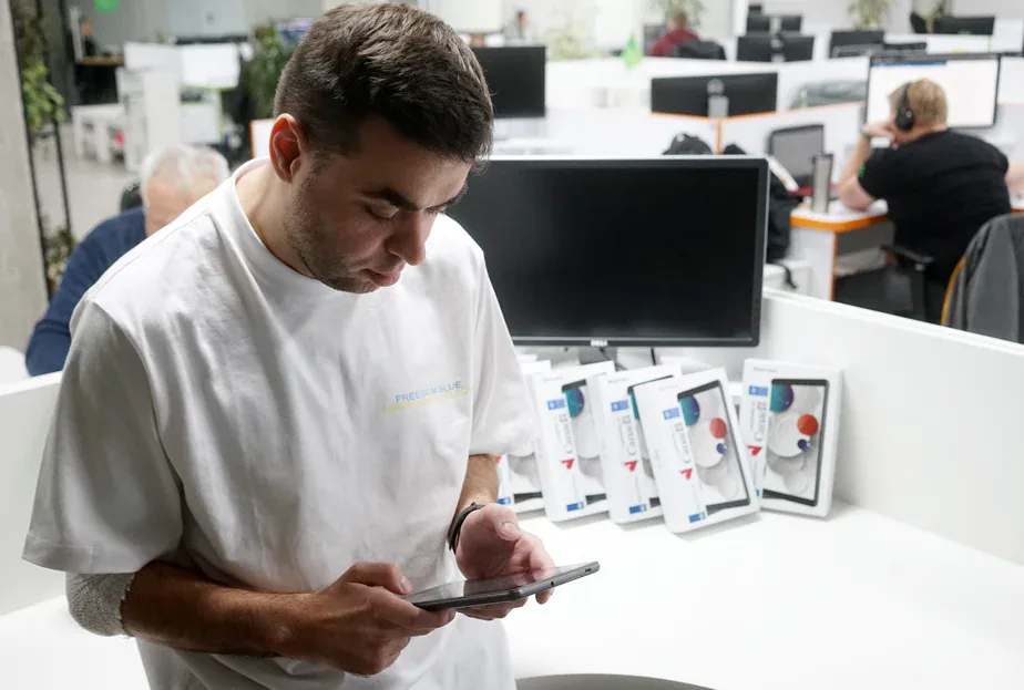 Man checking a tablet in an office, with a row of boxed tablets bearing Canada and UNDP labels on the desk