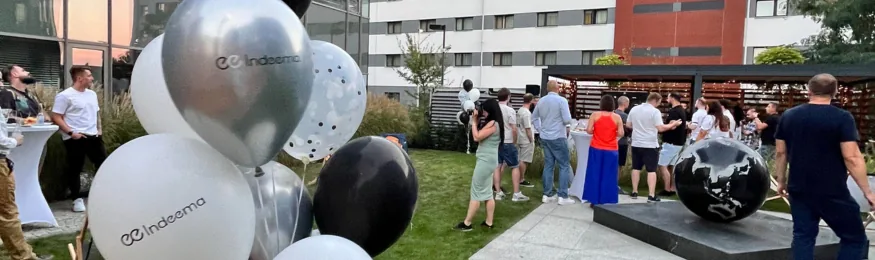 Office opening party in a courtyard, with Indeema-branded balloons in the foreground and guests mingling