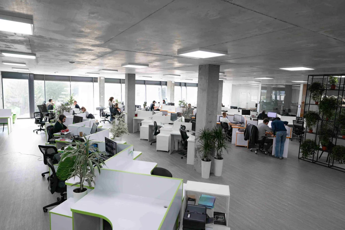 Bright open-plan Indeema office with rows of desks, engineers at work, concrete columns and potted plants