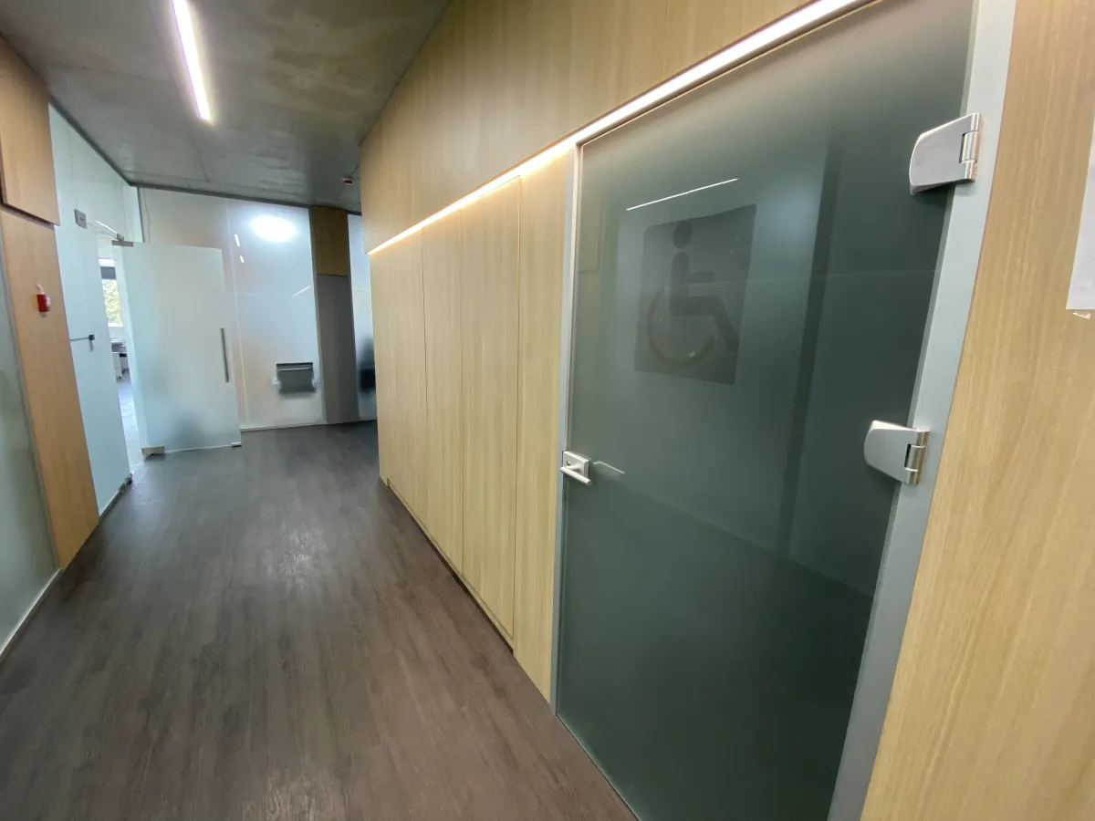Corridor with wood-panelled walls and a frosted glass door marked with a wheelchair accessibility symbol