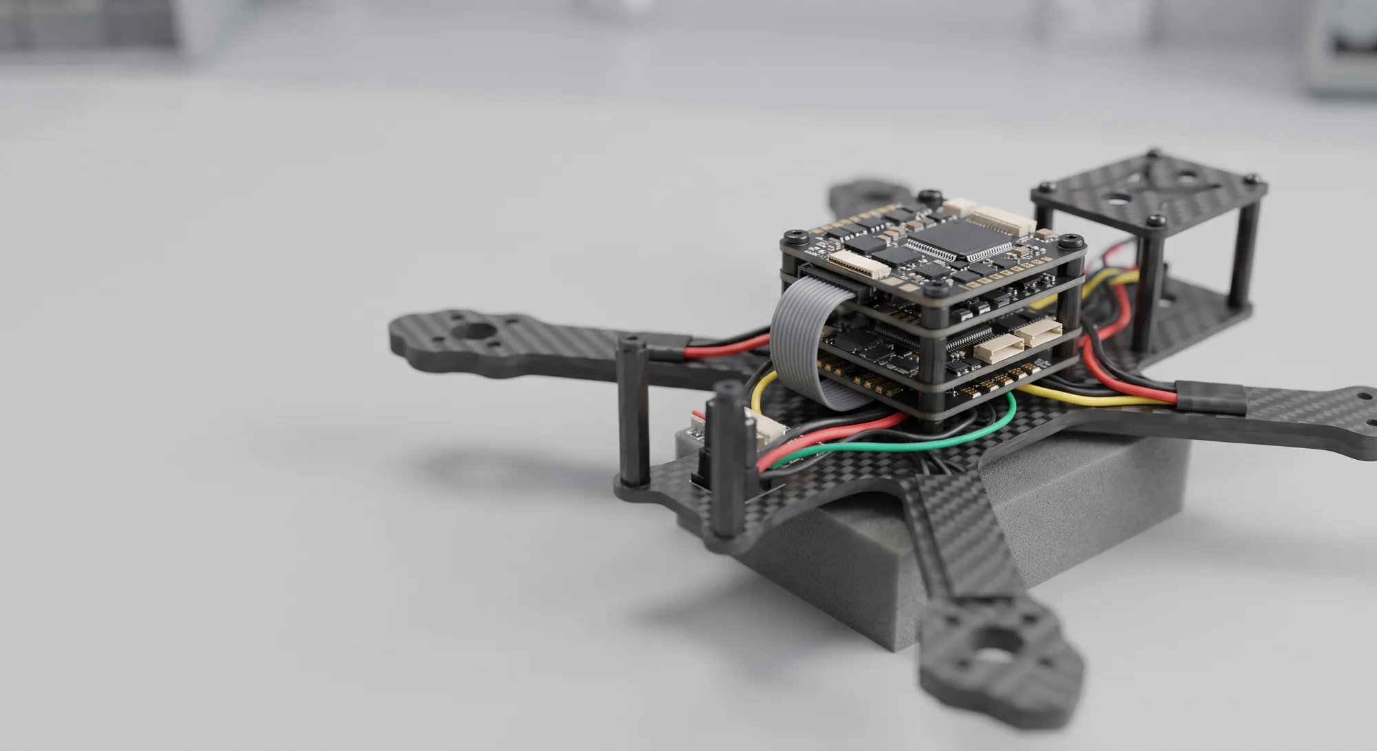 A small carbon drone airframe on a foam stand with its flight-controller and companion-computer stack exposed